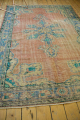 Distressed vintage Oushak rug texture with faded blush, blue, and aqua patterns.