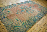 Distressed texture of the vintage Oushak rug corner, showing faded blue and aqua green border.