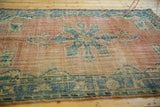 Secured end of the vintage Oushak rug, highlighting worn pile and faded blue border.