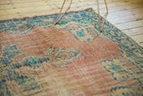 Corner detail of distressed Oushak carpet, with faded blush field, blue motifs, and visible foundation wear.