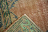 Distressed Oushak carpet corner, revealing mostly even wear, exposed foundation, and fringe.