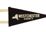 Cream-colored graphic and lettering on the black wool felt of a Westchester County pennant.