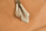 Close-up of a folded linen cocktail napkin with aqua blanket stitch and playful fringe.