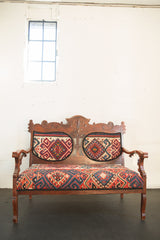 Intricately carved wooden backrest of the Kilim Upholstered Bench, featuring vibrant geometric upholstery.
