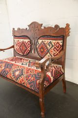 Vintage Kilim upholstered bench right armrest and leg, showcasing carved wood and geometric patterns.