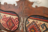 Intricately carved vintage bench backrest with ornate scrollwork and vibrant Kilim pattern.