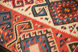 Close-up of vibrant geometric kilim flatweave in red, blue, cream, and orange.