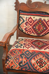 Intricate red, blue, beige geometric Kilim patterns on a vintage bench.