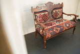 Vintage carved wood bench with vibrant geometric Kilim upholstery on seat and backrest.
