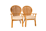Pair of vintage rattan armchairs with natural frames and light cream seat cushions.