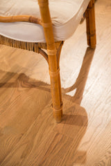 Rattan chair leg showing woven seat base detail and soft white cushion.