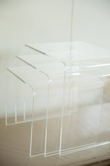 Vintage Lucite nesting tables, clear acrylic stacked forms with curved edges.