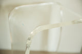 Clear, curved lucite leg detail on vintage end table with a subtle blue mark.