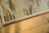 Close-up of vintage OM painting showing textured canvas and silver frame.