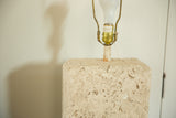Porous and pitted texture of the faux travertine lamp base with brass socket hardware.