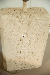 Close view of the porous and pitted texture of the faux travertine lamp base.
