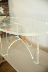 Thick oval Lucite coffee table top and clear crisscross base detail.