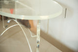 Thick clear Lucite oval tabletop edge and curved crisscross base detail.