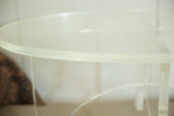 Close-up of thick oval Lucite tabletop edge with clear crisscross base.