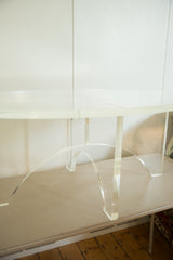 Vintage 1970s oval coffee table featuring a transparent Lucite crisscross base.
