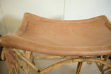 Vintage deerskin foot stool with curved tan seat, visible stitching, and bamboo frame.