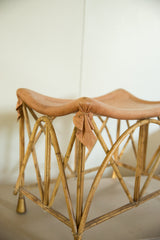 Intricate crisscross cane base of a vintage deerskin foot stool with golden feet.