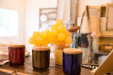 Vintage artificial stone grapes in bright citrine yellow, with stem, resting on cork lids.