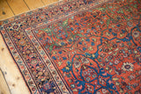Intricate floral arabesques and vivid patterns on antique Fereghan carpet's madder red field, showing even wear.