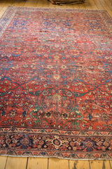 Antique Fereghan carpet detail: madder red field, intricate florals, navy border, and visible even wear.