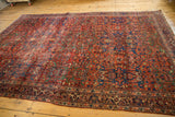 Antique Fereghan carpet's madder red field with scrolling arabesques, floral motifs, and visible wear.