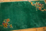 Emerald green field of the vintage Art Deco rug with asymmetric floral arrangements.
