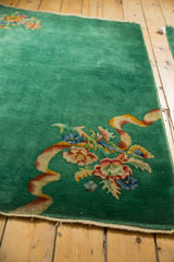 Intricate floral bouquet with expressive ribbon on emerald green vintage Art Deco rug.
