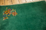 Emerald green field with floral motif and secured end of the Chinese Art Deco rug.