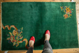 Ornate floral bouquet and ribbon motif on the vintage emerald green Art Deco rug.