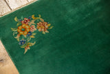 Emerald green main field showing pile texture and colorful Art Deco floral motif.