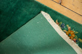 Ribbed green foundation and emerald pile of vintage Art Deco rug, revealing floral pattern.