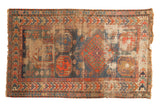 Antique Caucasian prayer rug, geometric medallion, navy, tangerine, and time-softened sand.