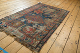 Geometric floral guls and colorful borders on the worn antique Caucasian rug.