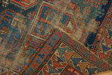 Folded antique Caucasian rug detail: geometric designs, navy blue, tangerine, and exposed natural foundation.