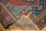 Malayer rug corner folded, revealing hand-knotted reverse, worn fringe, and sapphire blue patterns.