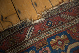 Malayer rug's aged, tattered fringe and detailed border with madder red and blue hues.