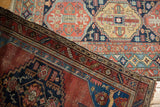 Antique Malayer rug corner: madder red field, sapphire blue spandrel, stylized creature motifs, mostly even wear.