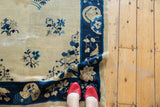 Curled corner of a Vintage Peking rug displaying cobalt blue border and bird motif.