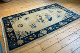 Vintage Peking rug corner: deep blue floral border, beige field, and secured end.