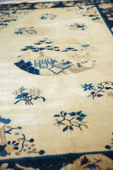 Peking rug's antique ivory field with cobalt blue pavilion and floral motifs.