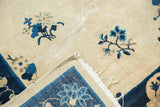 Vintage Peking rug's folded edge, showing ivory field, blue floral border, and wear.
