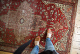Antique Persian Farahan Sarouk rug, detailed central medallion, terra cotta field, and knot wear.
