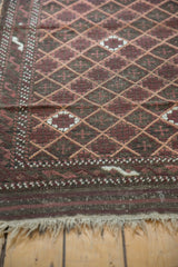 Secured fringe and geometric border of an antique Belouch rug, featuring wine and charcoal tones.