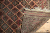 Intricate lattice design, plain weave end, and ivory fringe of an antique Belouch rug.