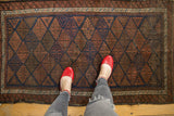 Antique Persian Belouch rug with paneled geometric lattice motifs in navy blue and rust.